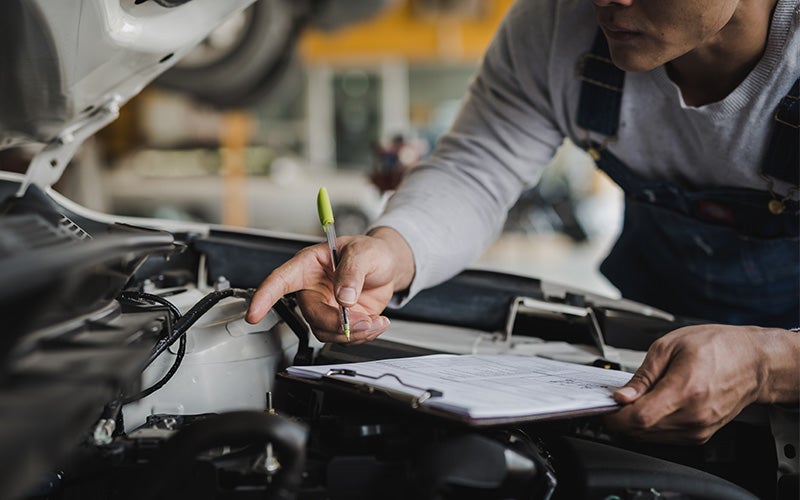 A mechanic looking under the hood of a vehicle